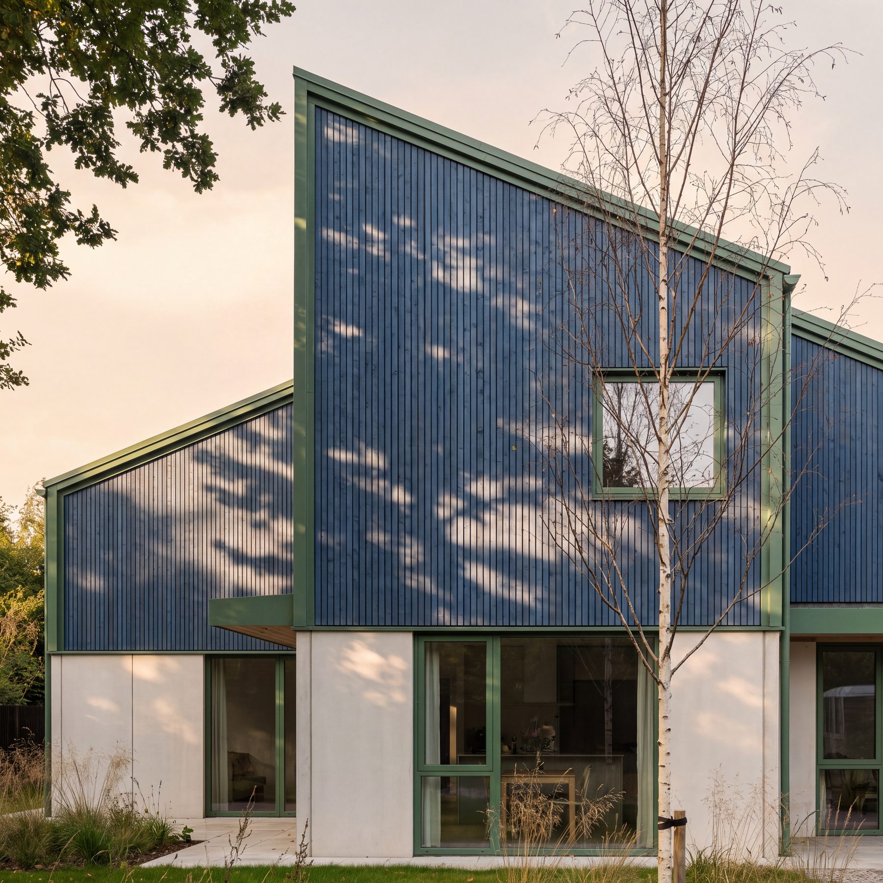 Timber-clad house with blue-black stain and green trim at dusk